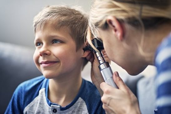 Médica observando el oído de un niño