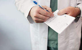 Doctor writing on a prescription pad.