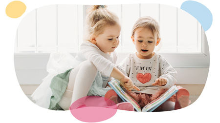 toddler sisters reading a book together