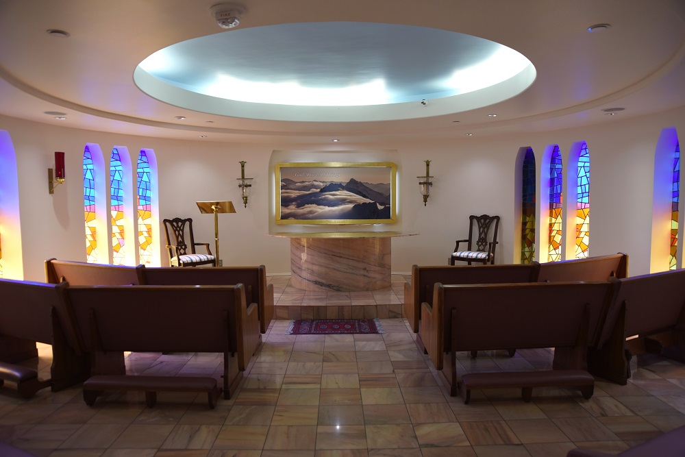 pequeña capilla con altar, vitrales y bancos.