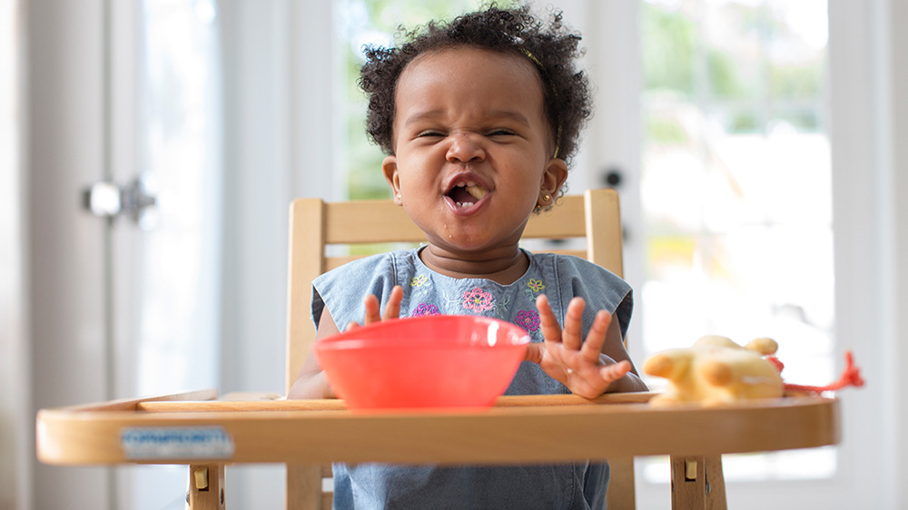toddler girl eating on a high chair