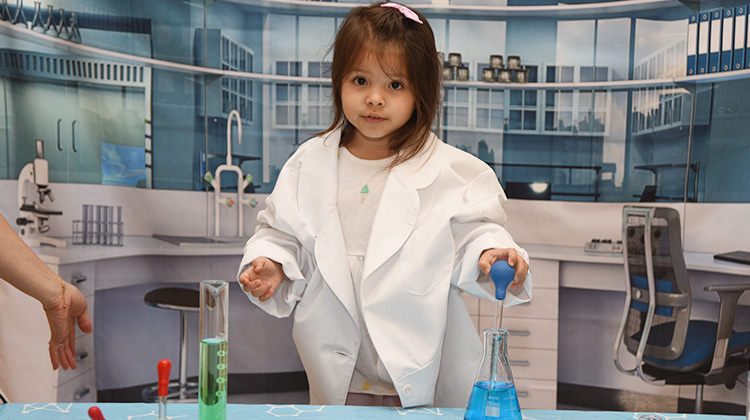 cute girl in an oversized lab coat playing with test tubes.