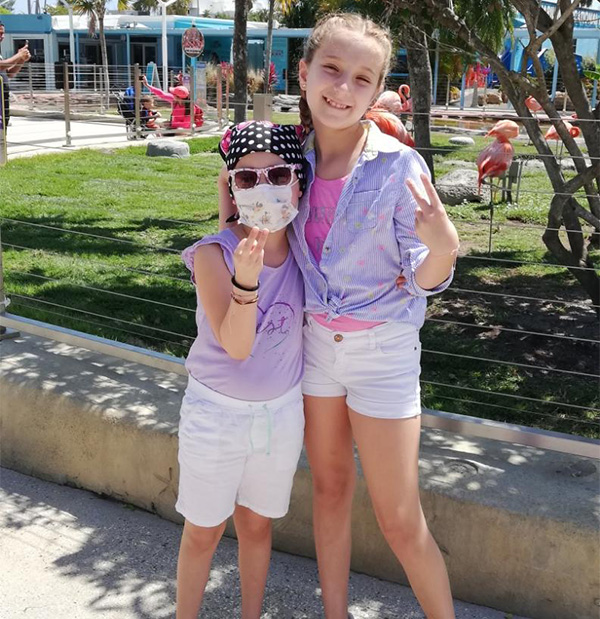 Isabella with her sister in front of pink flamingo enclosure.